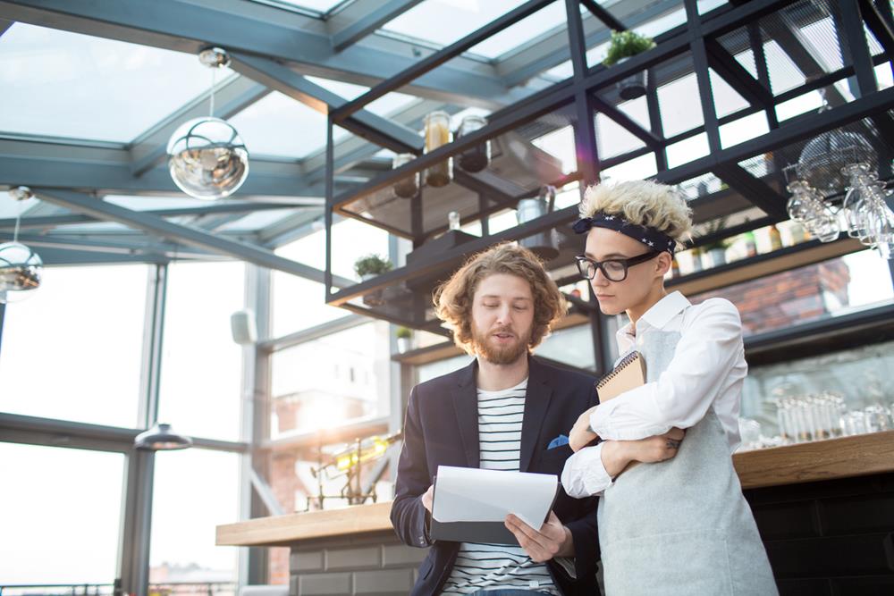 A restaurant supervisor talking to a waitress and showing a document