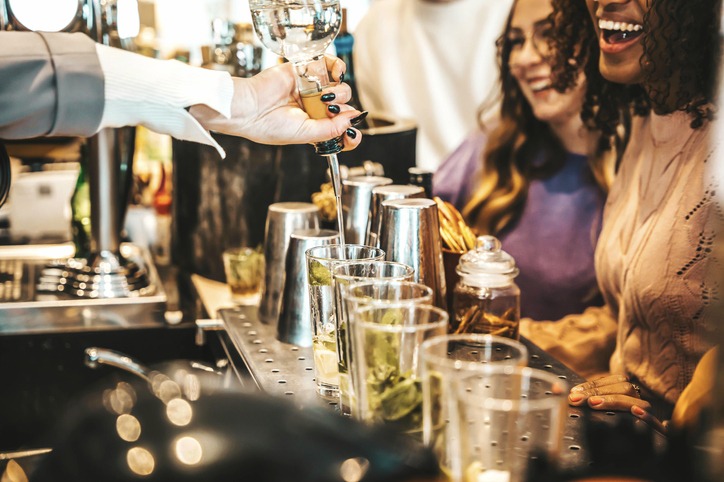 Happy group of friends being served drinks by a bartender