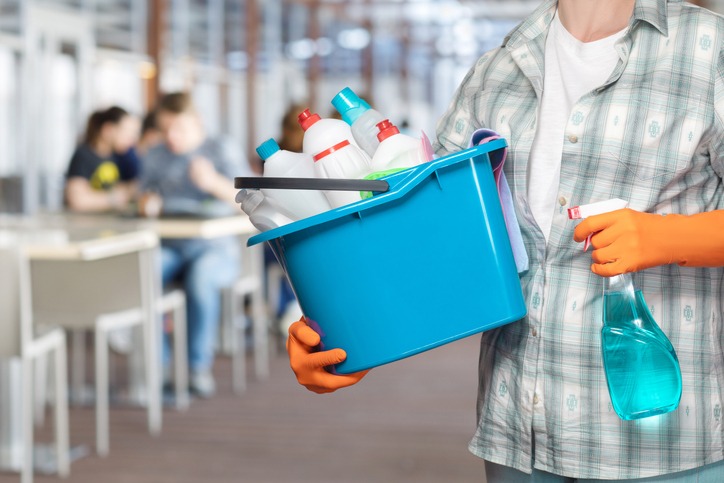 a busser holding a bucket of cleaning products