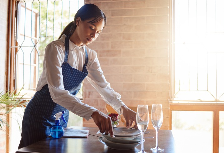 waitress cleaning dishes from the table 