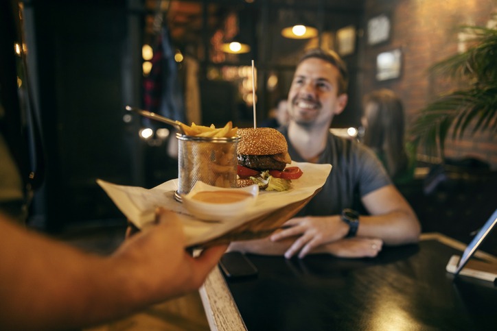 a hand bringing food to a man in a restaurant