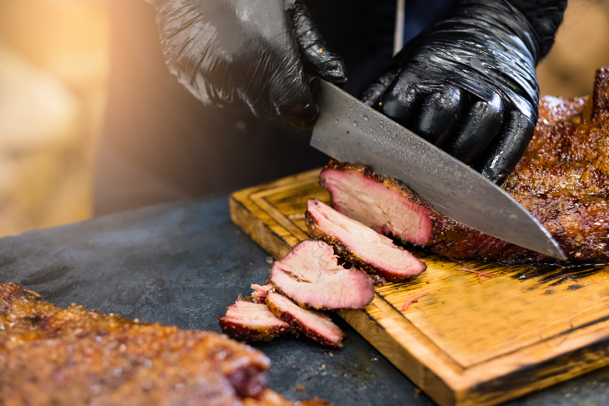 A server slicing smoked brisket