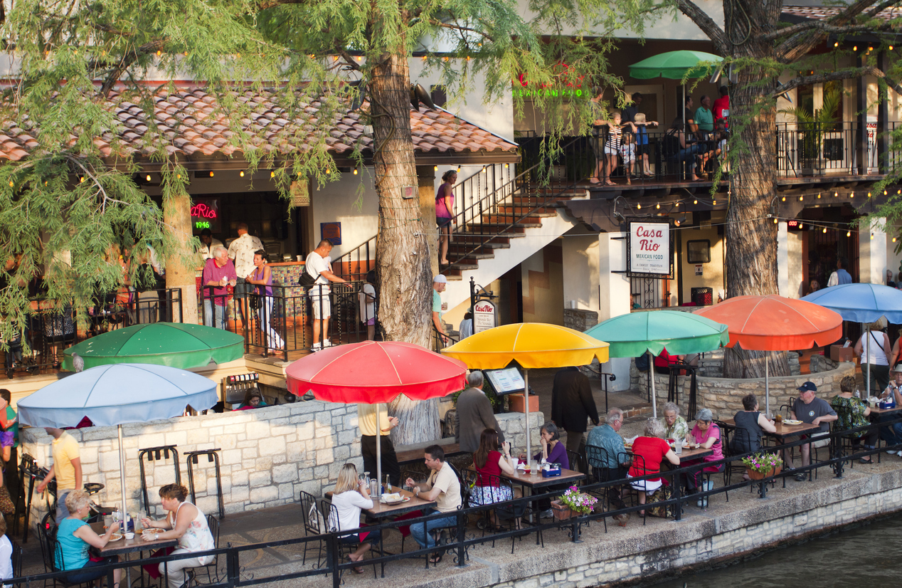 San River Walk with crowds of tourists dining under bright umbrellas