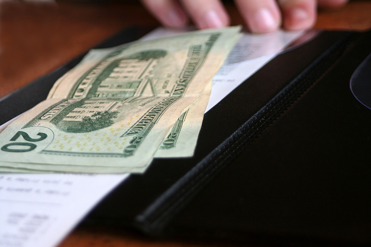 Money and receipt being placed on the payment binder for payment of a meal