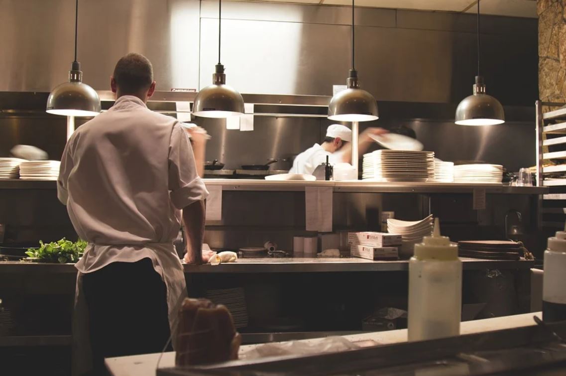 Image of cooks and servers working in a kitchen of a restaurant