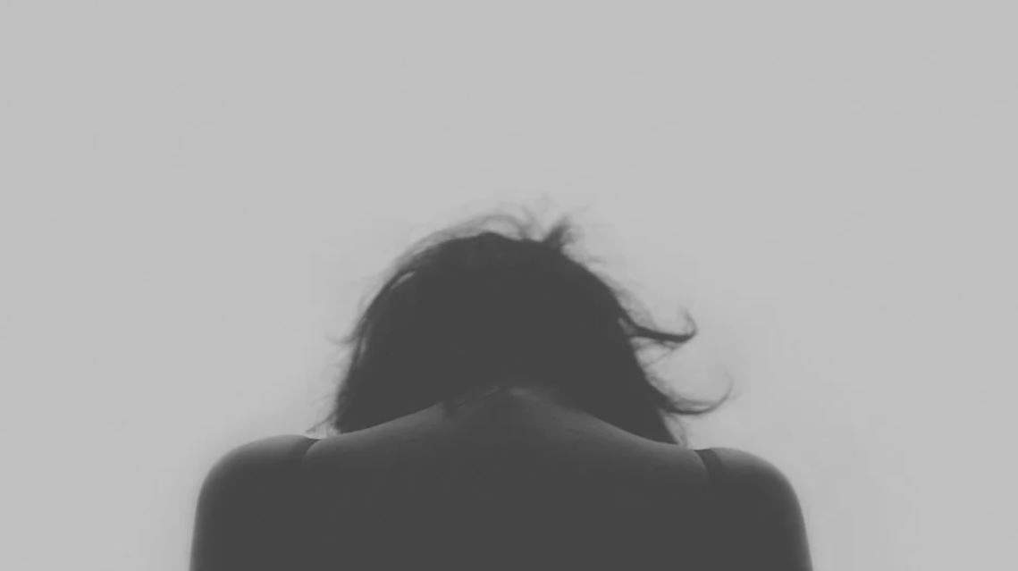 Alt-text: Picture of a silhouette of a woman from behind depicting low self esteem and depression.