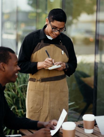 a server taking an order while smiling on his smartphone