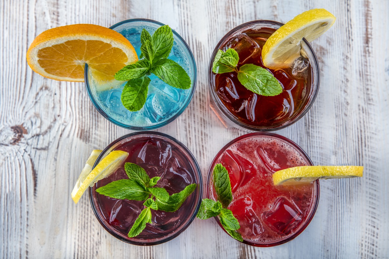four fruity cocktails with fresh fruit and herb